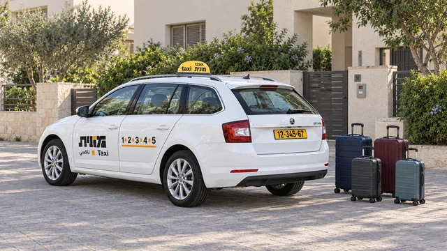מונית סטיישן ישראלית לבנה עם דלת תא מטען סגורה, ולצדה ארבע מזוודות בשני גדלים ברחבה מרוצפת ליד בית.